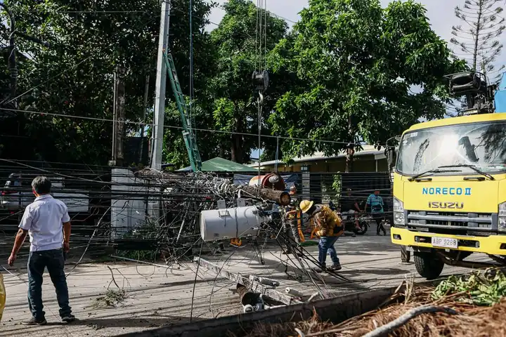 Team of workers in hard hats repairing electrical lines from a fallen pole after an accident.